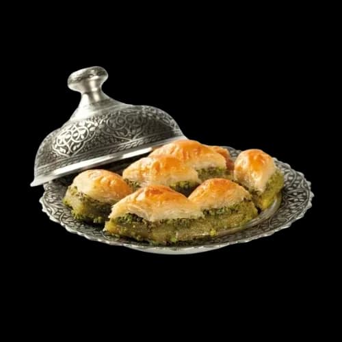 Silbertablett mit frischem Pistazien-Baklava unter einer verzierten Servierhaube